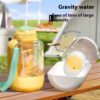 343bdf46-a504-43c4-a420-3e21fd036624_trans.jpeg Yellow gravity water bottle with teal strap beside a white baby bottle warmer on a wooden outdoor table.